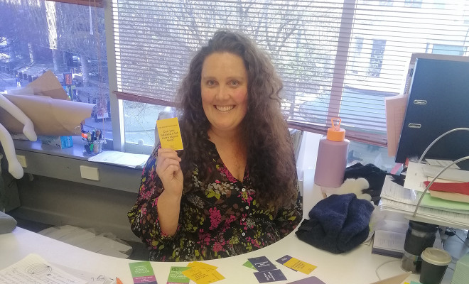 Whitecliffe staff member holding up a conversation card used to help improve professional conversations