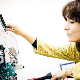 A student adjusts settings on a sewing machine