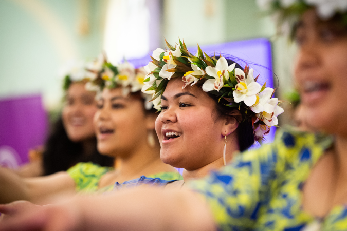 Pacific singers adorned with colorful head garlands performing together. 