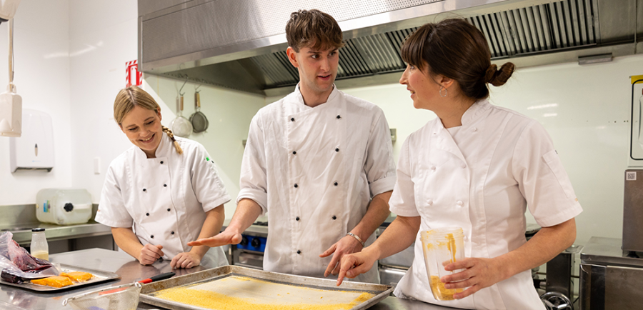 Juliane Tautz and Chloe Humphreys guide a student through a recipe
